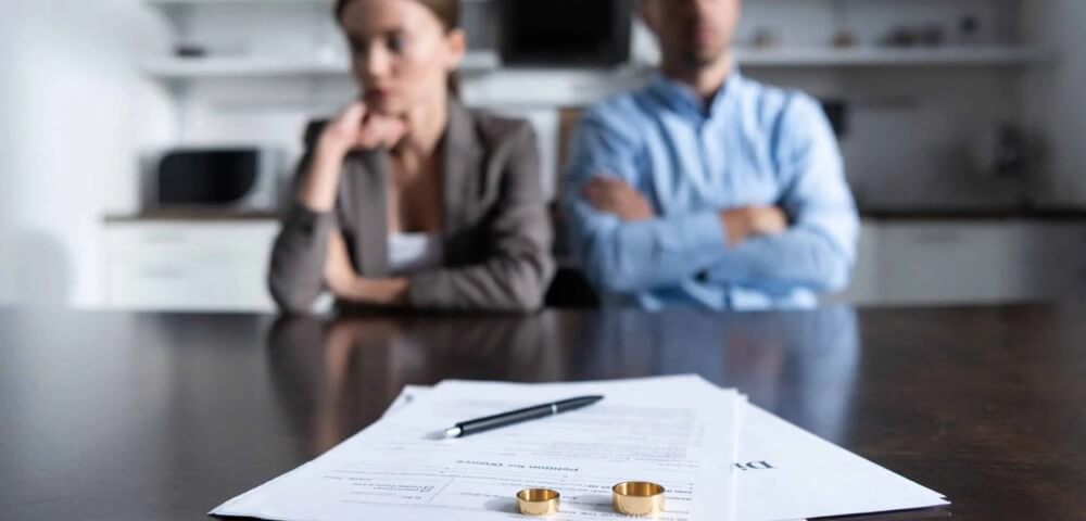 Herfinancieer je hypotheek bij een scheiding selective focus of couple sitting at table with divorce documents