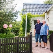 Ouder koppel staat gearmd voor hun woning, symbool voor kredieten hergroeperen na uw 50ste