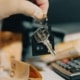 Sleutel met huisvormige hanger naast een rekenmachine en geld, symbool voor variabele hypotheekrente die fors is gestegen