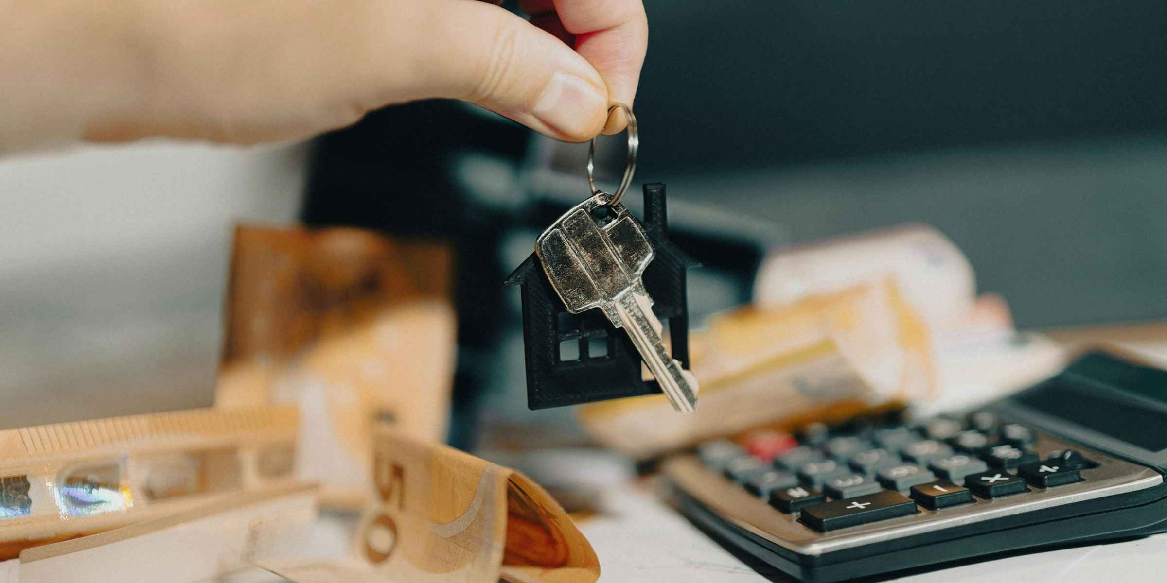 sleutel-huisvormige-hanger-rekenmachine-geld Sleutel met huisvormige hanger naast een rekenmachine en geld, symbool voor variabele hypotheekrente die fors is gestegen